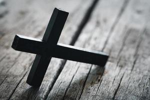 A wooden Christian cross crucifix on a grunge board background. Wooden Christian cross on grey table against blurred lights, space for text. photo