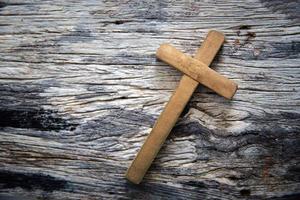un de madera cristiano cruzar crucifijo en un grunge tablero antecedentes. de madera cristiano cruzar en gris mesa en contra borroso luces, espacio para texto. foto