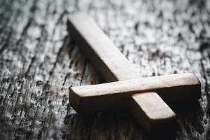 A wooden Christian cross crucifix on a grunge board background. Wooden Christian cross on grey table against blurred lights, space for text. photo