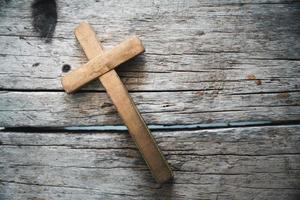 A wooden Christian cross crucifix on a grunge board background. Wooden Christian cross on grey table against blurred lights, space for text. photo