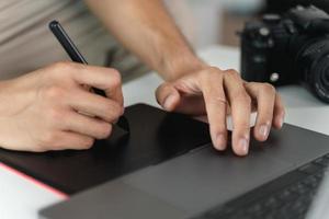 hombre diseñador utilizando bolígrafo ratón tableta dibujo y escritura en tableta tablero con aguja para retocando, y gráfico diseño. foto