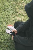 young man sitting on the ground in the park, completely immersed in his smartphone. photo