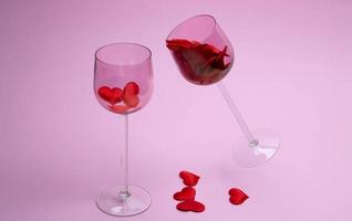 Two glass glasses on a pink background filled with red hearts. The concept of love, family, loyalty photo