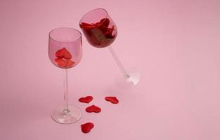 Two glass glasses on a pink background filled with red hearts. The concept of love, family, loyalty photo