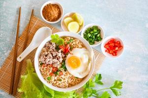 noodles bowl with boiled egg minced pork vegetable spring onion lemon lime lettuce celery and chili on table food , instant noodles cooking tasty eating with bowl noodle soup photo