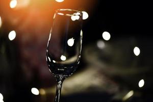 Champagne glass on table against blurred lights background - perspective of crystal clear wine glass for night party on the counter top bar restaurant photo