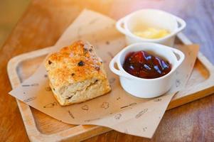 scones and jam on wooden plate, served scones and cream for dessert and tea - fresh homemade butter scones photo