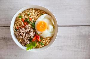 noodles bowl with boiled egg minced pork vegetable spring onion lemon lime lettuce celery and chili on table food , instant noodles cooking tasty eating with bowl noodle soup photo