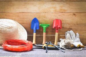 Gardening tools on wooden background with pliers straw hat , rope , gloves trowel garden equipment photo