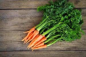 zanahoria sobre fondo de mesa de madera, zanahorias frescas y dulces para cocinar frutas y verduras para el concepto de salud, manojo de zanahorias para bebés y hojas foto