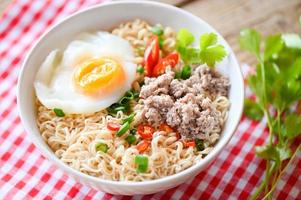 noodles bowl with boiled egg minced pork vegetable spring onion lemon lime lettuce celery and chili on table food , instant noodles cooking tasty eating with bowl noodle soup photo