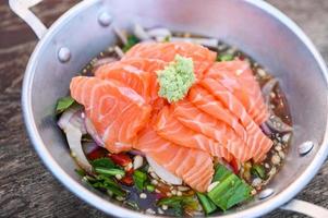 salmon fillet with wasabi on spicy sauce , fresh raw salmon salad on wooden table - Thai food photo