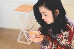 young woman drinking coffee or tea relaxed woman smelling coffee at home in winter with cup coffee, woman coffee with hand holding a cup in cafe photo