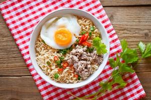 noodles bowl with boiled egg minced pork vegetable spring onion lemon lime lettuce celery and chili on table food , instant noodles cooking tasty eating with bowl noodle soup photo