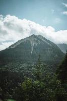 majestuoso montañas en el Alpes cubierto con arboles y nubes foto