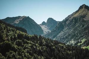 majestuoso montañas en el Alpes cubierto con arboles y nubes foto