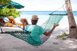 hombre en un hamaca por el playa foto