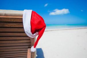 broncearse silla con Papa Noel sombrero en el playa foto