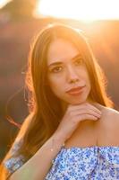 atractivo esbelto contento niña en un azul vestir en un lavanda campo a puesta de sol. foto