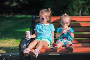 pequeño hermanas en un parque banco foto