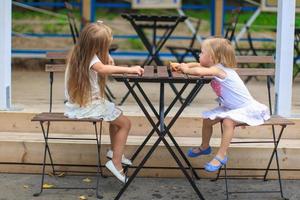 pequeño muchachas sentado en al aire libre comida zona foto