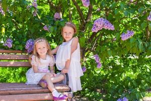 Little sisters with flowers in the garden photo