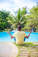Man meditating by the pool photo