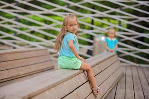 pequeño niña en un de madera banco foto