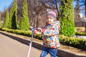 Little girl riding a scooter outdoors photo