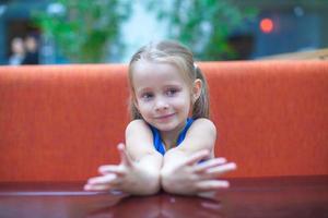 Little girl seated on a booth photo