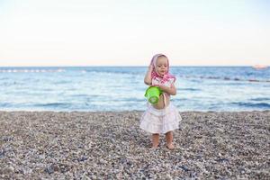 Cuttle little girl on the beach photo