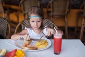 pequeño niña teniendo desayuno foto
