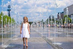 Little girl playing on a water fountain photo