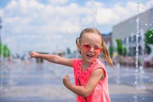 Little girl playing on a water fountain photo