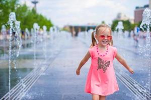 Little girl playing on a water fountain photo