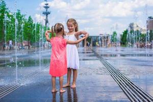 Little girls playing on a water fountain photo