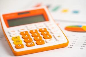 calculadora en tabla y papel cuadriculado. desarrollo financiero, cuenta bancaria, estadísticas, economía de datos de investigación analítica de inversiones, comercio bursátil, concepto de empresa comercial. foto