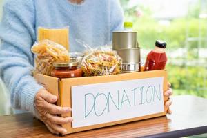 voluntarios poniendo varios alimentos secos en cajas de donación para ayudar a las personas. foto