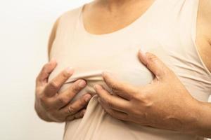 Asian woman patient checking and worry her breast, Breast Self Exam or BES, symbol of World Breast Cancer Day. photo