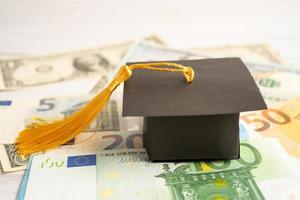 Sombrero de brecha de graduación en billetes de euro y dólar estadounidense, concepto de enseñanza de aprendizaje de tarifa de estudio de educación. foto