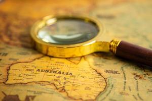 Bangkok, Thailand January 20, 2022 Australia, Magnifying glass close up with vintage old antique world map, travel, geography, tourism and exploration concept. photo