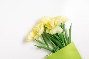 Mock-up of a paper shopping bag with tulip flowers lying on a white background. Spring, Easter sale. The concept of environmental friendliness and the absence of waste. photo