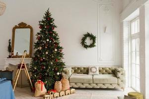 luxurious interior of the living room in a classic style. Sofa, Christmas tree with gifts by the fireplace photo