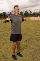 Mature man outside on the grass doing Stretches before working out photo