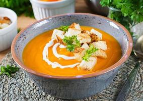 Pumpkin soup in a bowl served with parsley and croutons. Vegan soup. Thanksgiving day food. Halloween meal. photo