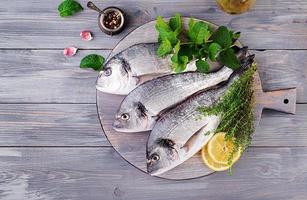 Raw dorado fish with green herbs cooking on cutting board. Top view photo