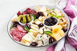 Antipasto platter with basturma, salami, blue cheese, nuts, pickles and olives on a white wooden background. photo