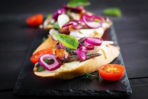 Tapas - Spanish bar food. Bruschetta with slices of sun-dried tomatoes,cheese mozzarella and anchovies on dark background. photo