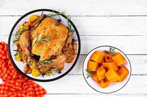 Roasted turkey garnished with cranberries on a rustic style table decorated  autumn leaf. Thanksgiving Day. Baked chicken. Top view photo