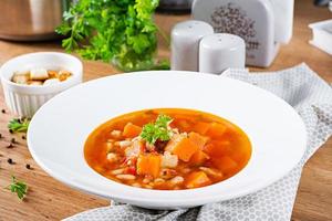 Tomato chicken soup with pumpkin and white beans in white bowl. photo